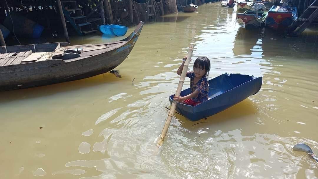 A young girl paddling alone through the floating village