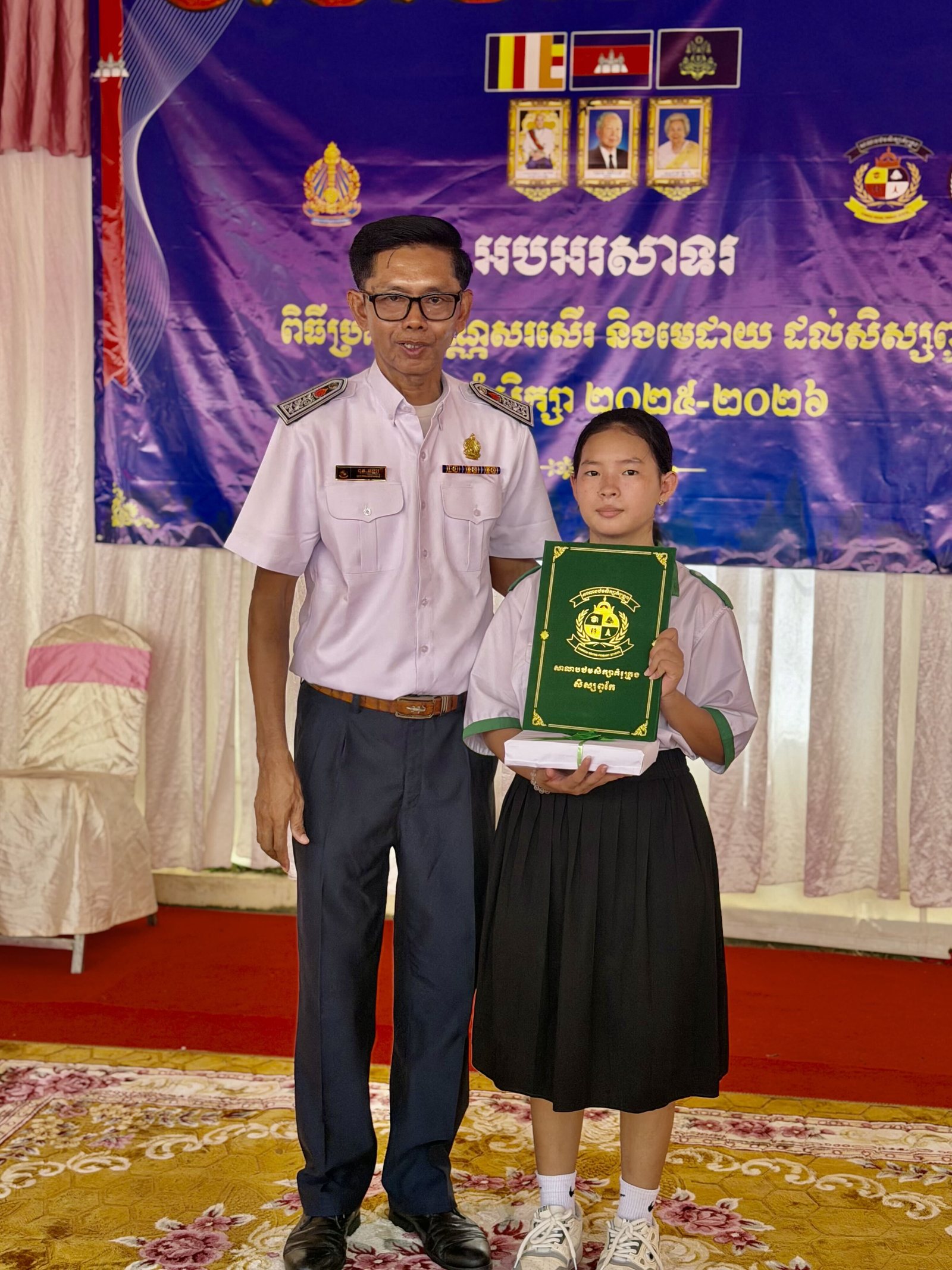 A student receiving her certificate from a Cambodian school official