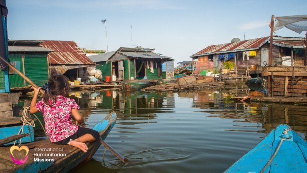 A little girl in pink, paddling a boat through the floating village of Tonle Sap, Cambodia
