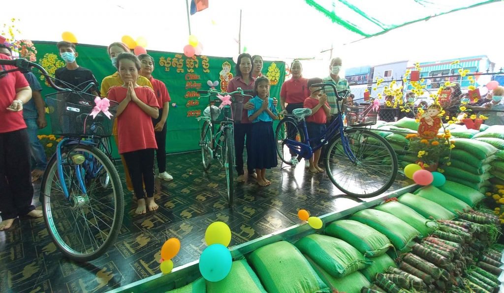 The bicycle raffle winners standing with their new bikes and families, surrounded by bags of rice and Tết decorations